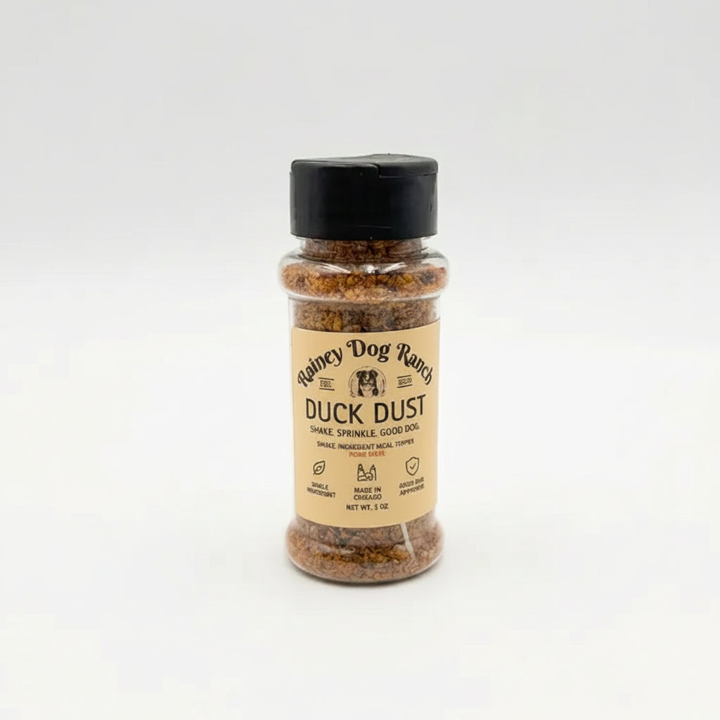 A small clear plastic bottle of Rainey Dog Ranch Duck Dust seasoning with a black cap and a tan label, centered on a light gray background.