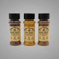Three spice seasoning bottles labeled 'Rainey Dog Ranch' on a light gray background: Buck Dust, Fry Dust, and Duck Dust.