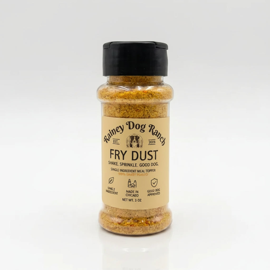 A bottle of Rainey Dog Ranch Fry Dust seasoning with a black cap and beige label, filled with a golden-brown spice blend, set against a clean white background.